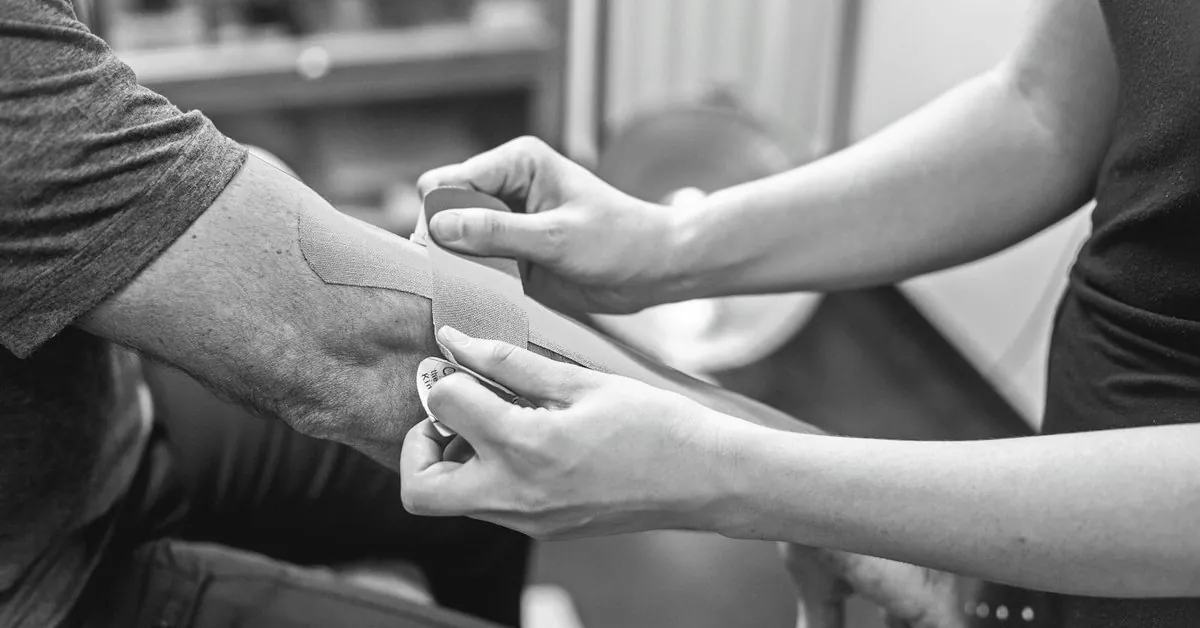 Aplicación de vendaje terapéutico sobre el codo en el tratamiento de la epicondilitis.